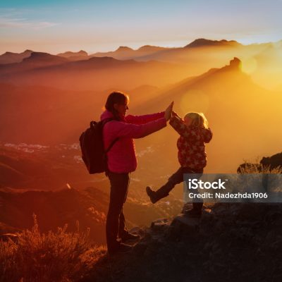 mother with little daughter enjoy travel in sunset mountains, family hiking